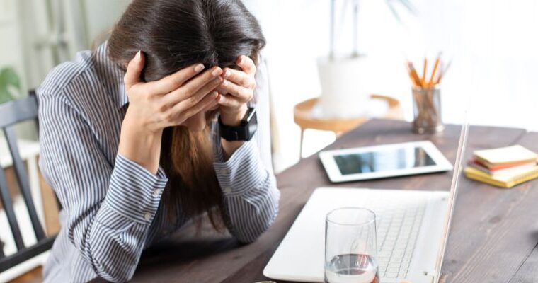 A real estate investor at her laptop with her head in her hands after making a common mistake - ECF