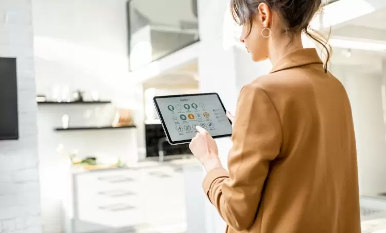 A home owner holding a tablet with real estate technology apps to make it a smart building - Express Capital Financing
