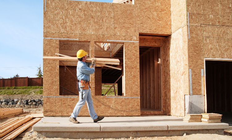 A joiner carrying materials at a new build property under construction - Financing a New Home Build - ECF