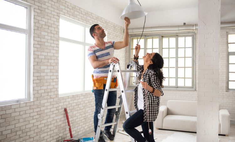 a couple fixing a lamp to the ceiling - fix and flip