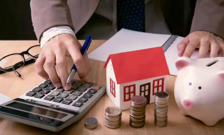 a person using a calculator with a small house in the foreground