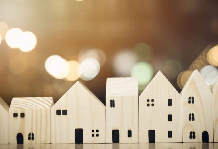 a row of small wooden models of houses in front of twinkling lights