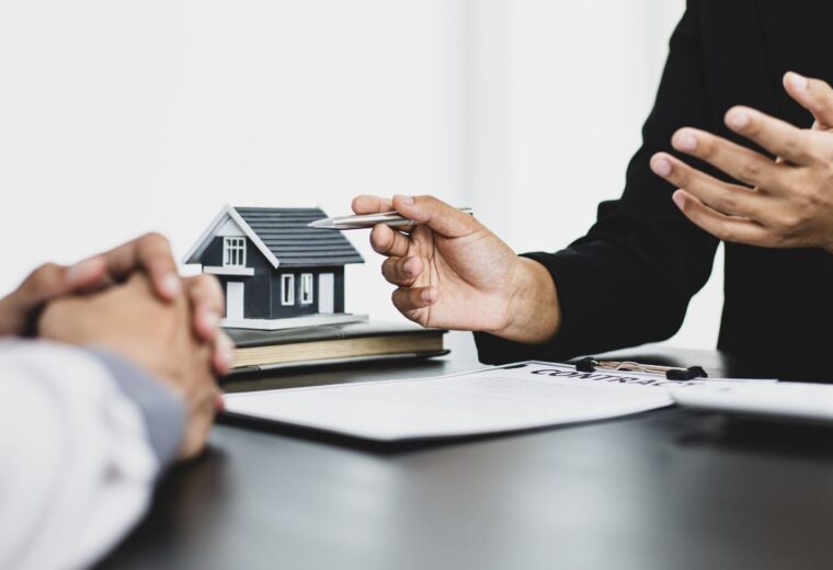Two men discussing paperwork with a small house in the background - Express Capital Financing