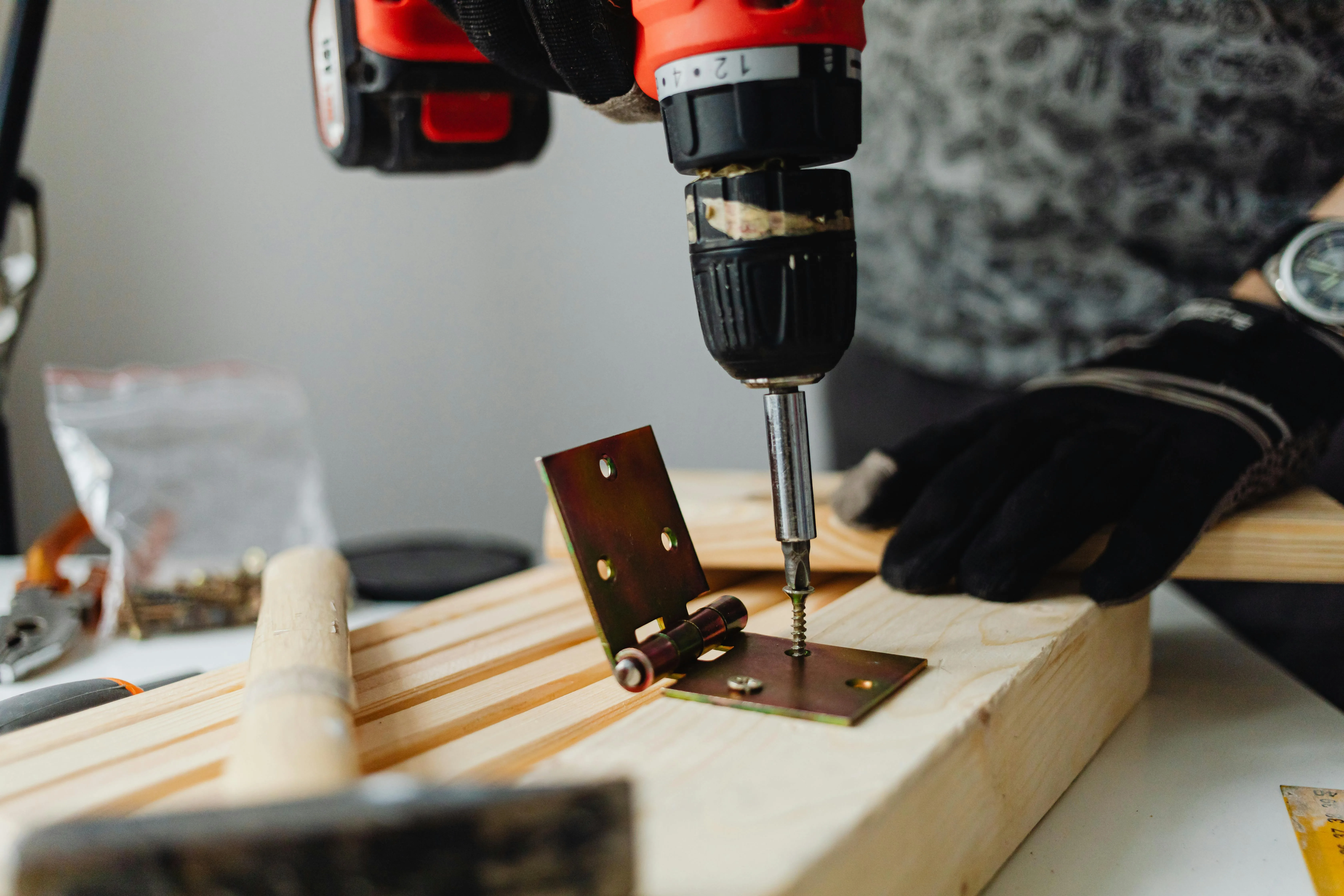 A hinge being drilled into a plank of wood - Express Capital Financing